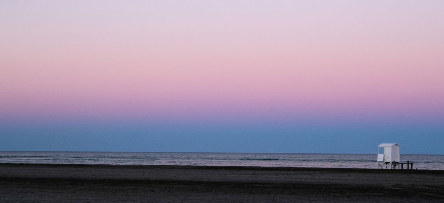 Beach at dusk with a pink sky and a lifeguard hut